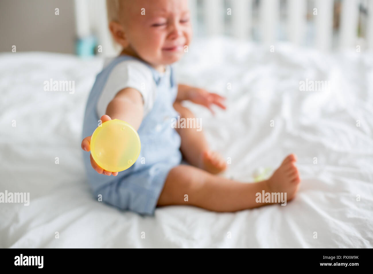 Toddler baby boy, playing with dummy, crying unhappy for the pacifier