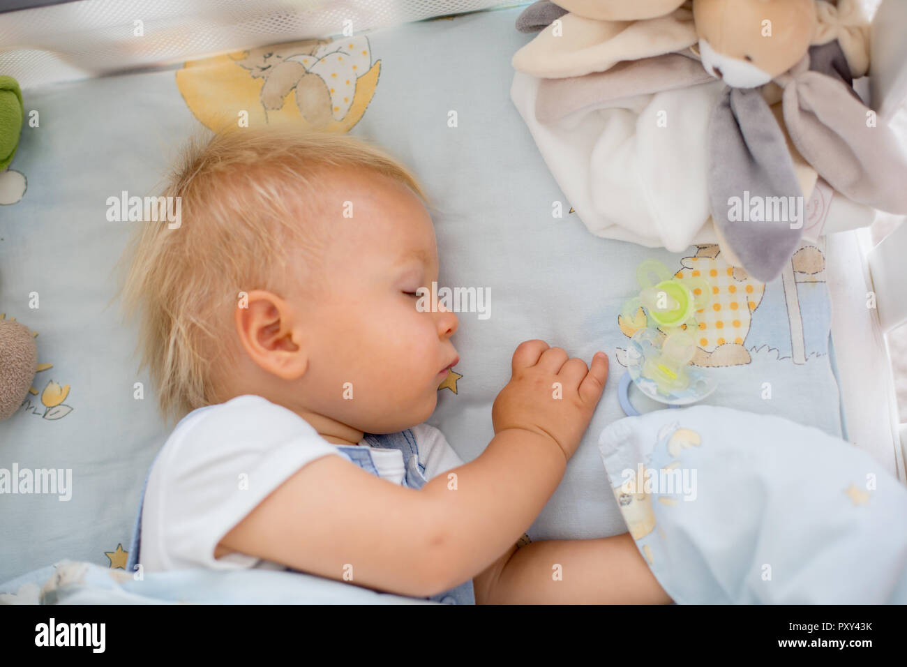 Little baby boy, sleeps in baby bed with pacifier nearby Stock Photo