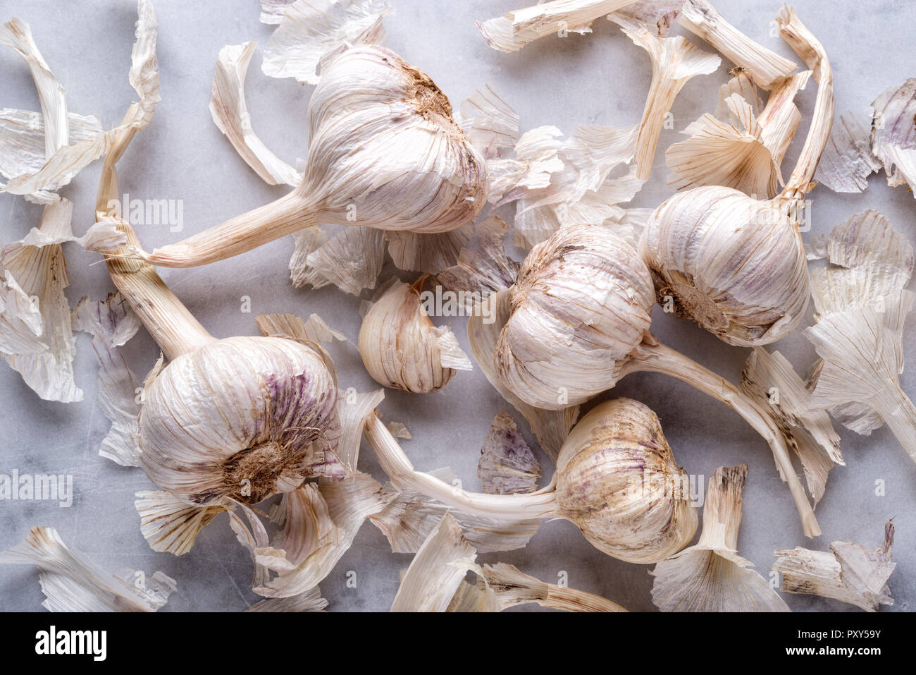 Fresh raw organic garlic flat lay on a white marble table top. Stock Photo