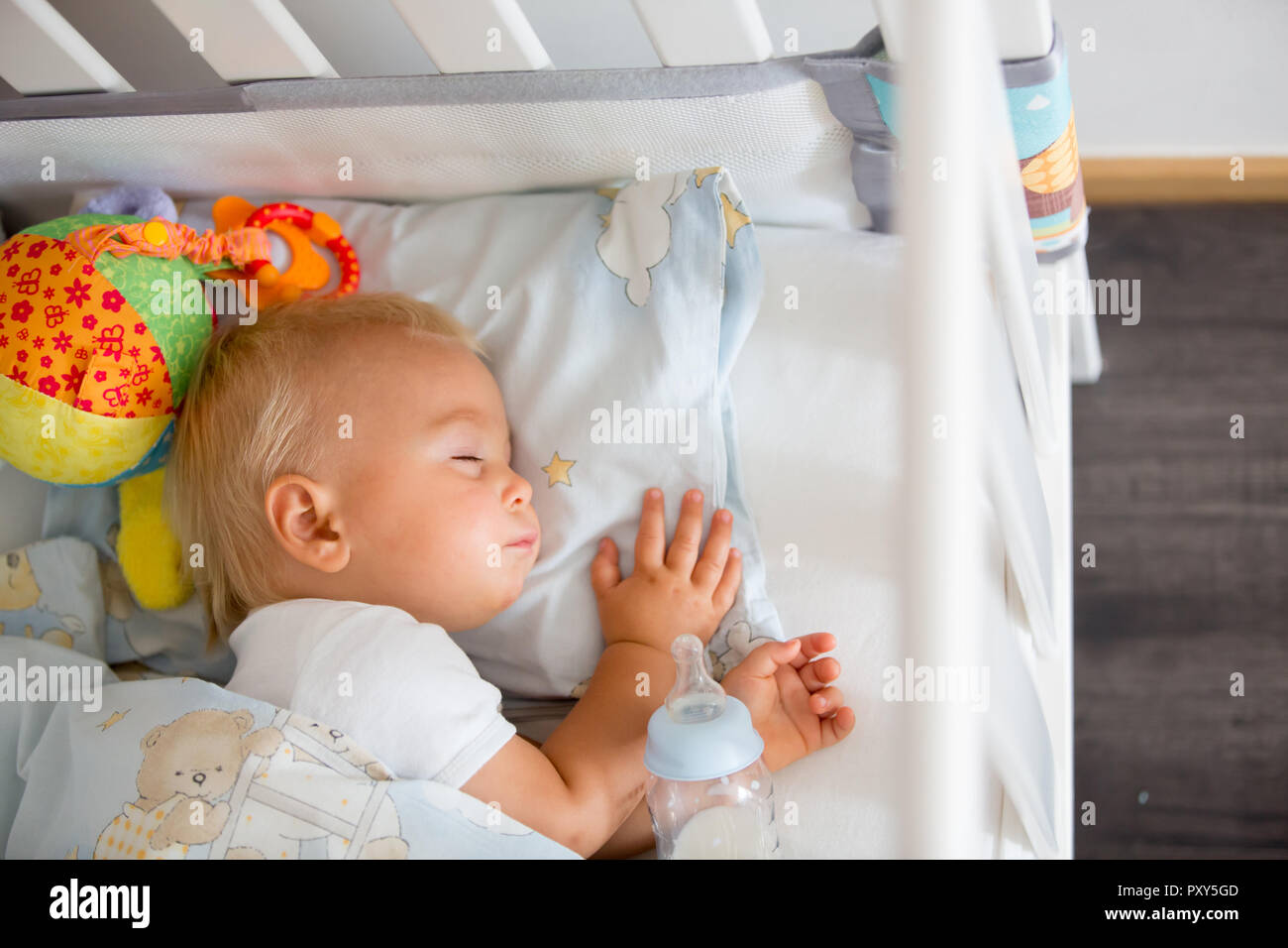 Cute little baby boy, sleeping with bottle with formula milk. Tired