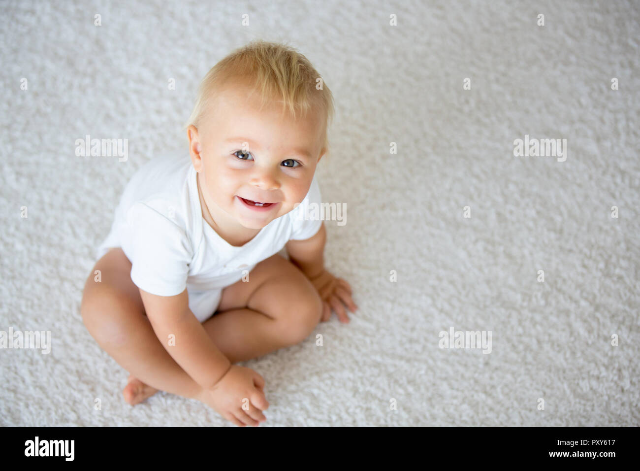 Cute baby boy, smiling and sitting at home in living room Stock Photo