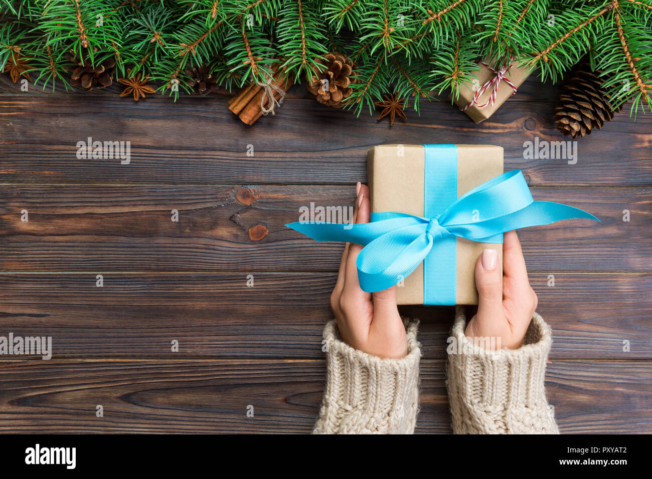 Female hands holding handmade present box in recycled paper on dark ...