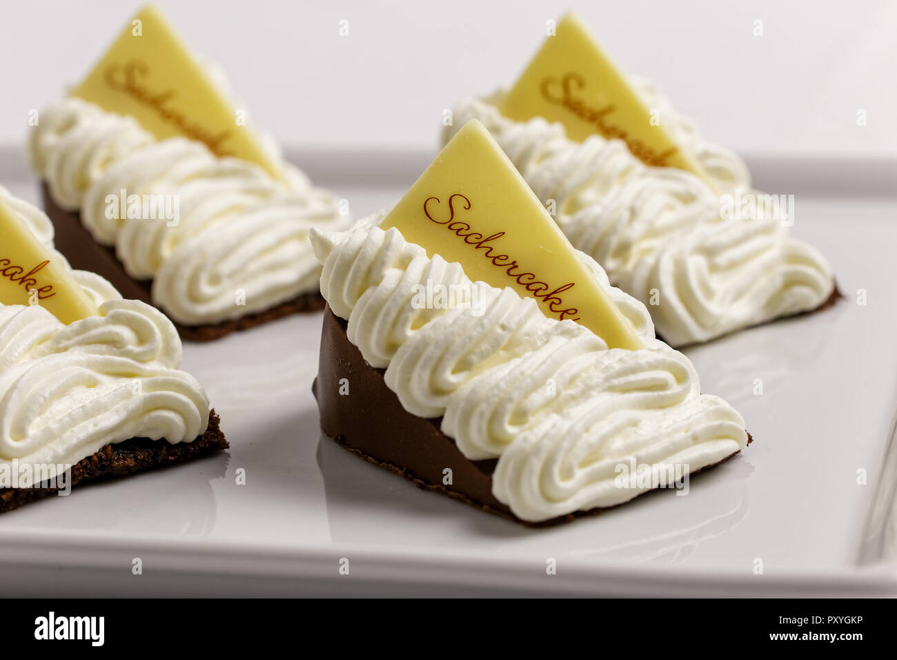 Closeup of four portions of  sacher cake decorated with cream on white tray. Stock Photo