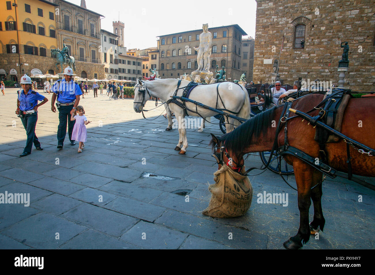 FLORENCE Tuscany Italy,little girl with two policemen at Piazza della Signoria where horses have a food break Stock Photo