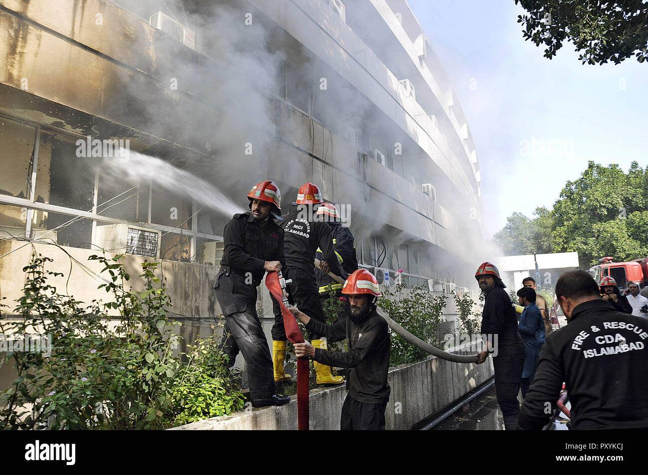 Islamabad. 24th Oct, 2018. Fire fighters try to extinguish fire from