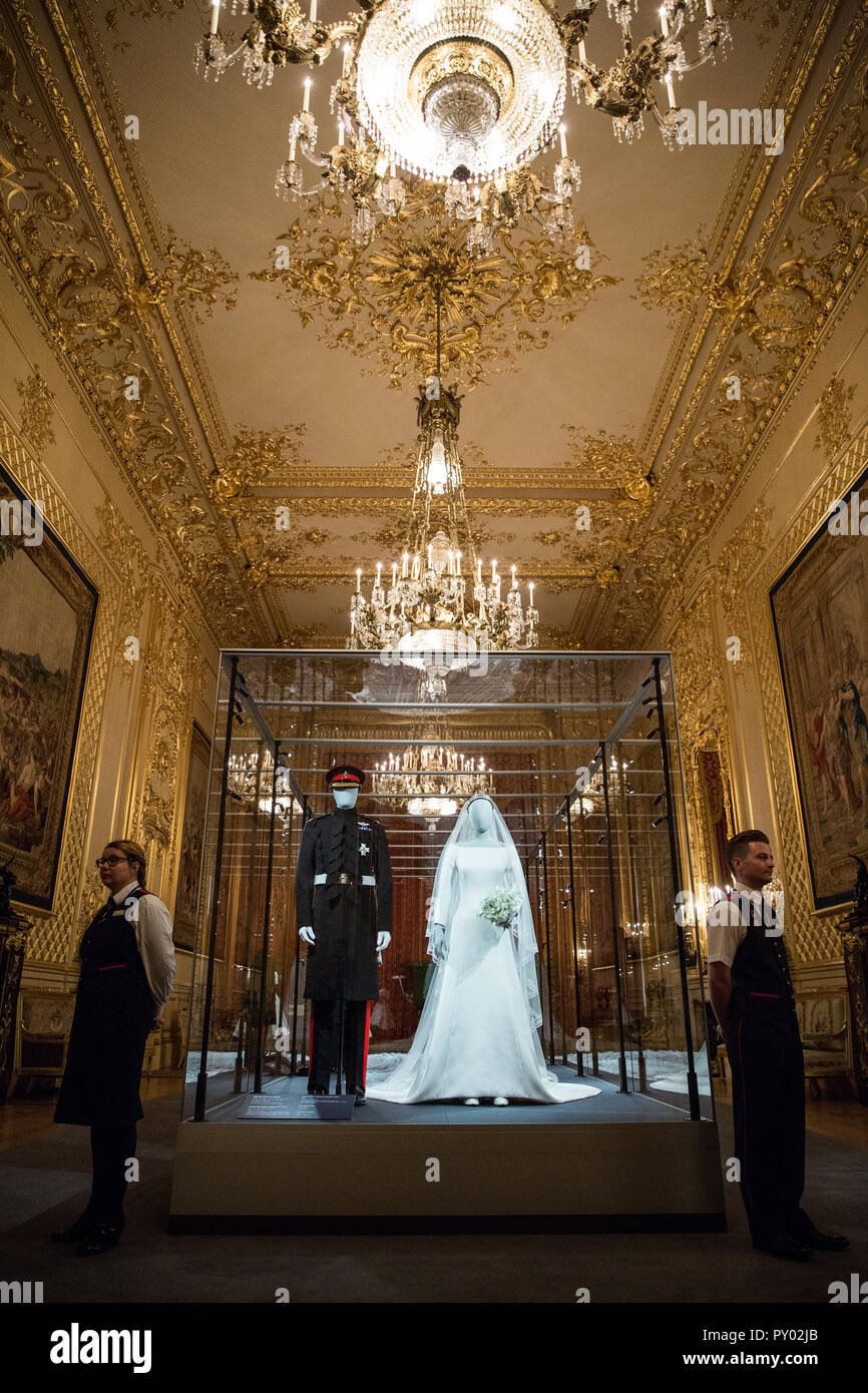 Windsor, UK. 25th October, 2018. IMAGE EMBARGOED FOR PUBLICATION UNTIL 00:01 BST, FRIDAY, 26 OCTOBER. Windsor Castle staff members pose next to the Duchess of Sussex’s wedding dress, created by the British designer Clare Waight Keller, Artistic Director at the historic French fashion house Givenchy, and the Duke of Sussex's frockcoat uniform of the Household Cavalry, which will go on display from 26th October 2018 to 6th January 2019 as part of a special exhibition entitled 'A Royal Wedding: The Duke and Duchess of Sussex'. Credit: Mark Kerrison/Alamy Live News Stock Photo