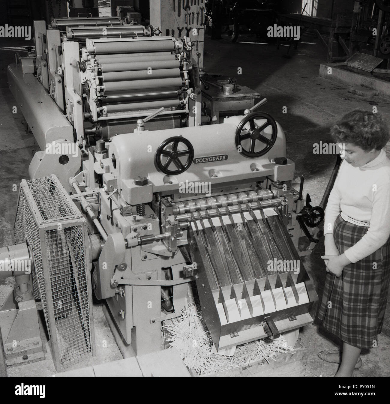 1950s, historical, a female worker standing by a large long printing machine, showing the extensive number of rotation inking rollers used in the printing process. Stock Photo
