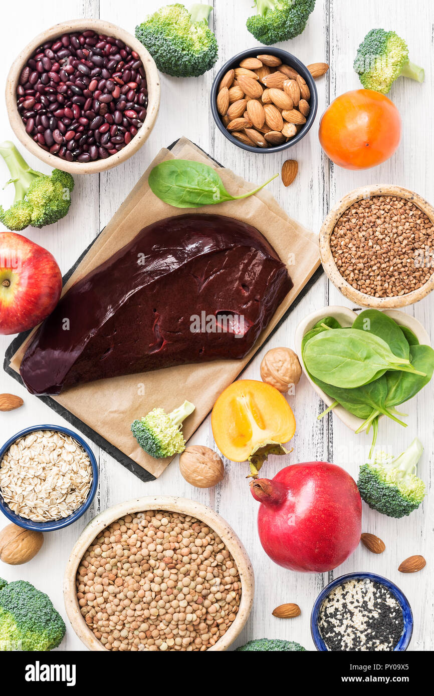 Food rich in iron, fruits, vegetables, cereals, spinach, beef liver on white rustic wooden background. The view from the top. Products with high iron  Stock Photo