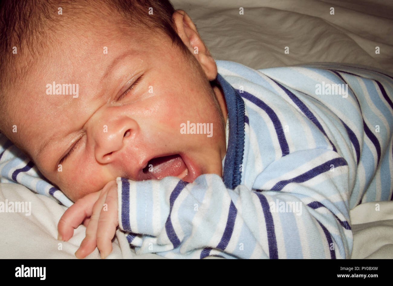 Two Weeks Old Newborn Baby Boy Sleeping On White Sheet Close Up Two Weeks Old Newborn Baby Boy Sleeping On White Sheet Close Up