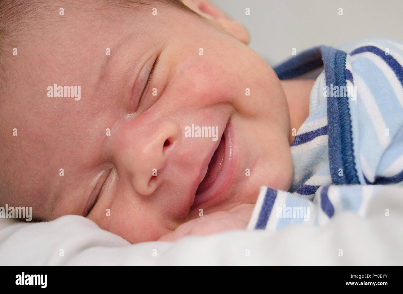 two weeks old newborn baby boy smilleing while sleeping close up Stock