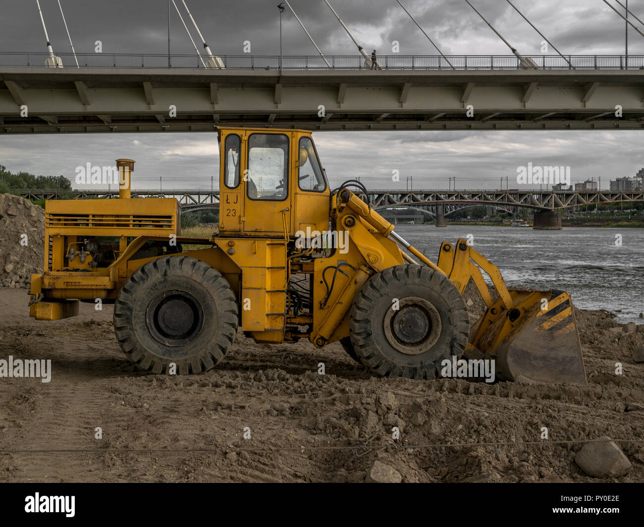 A yellow bulldozer next to a bridge. Stock Photo