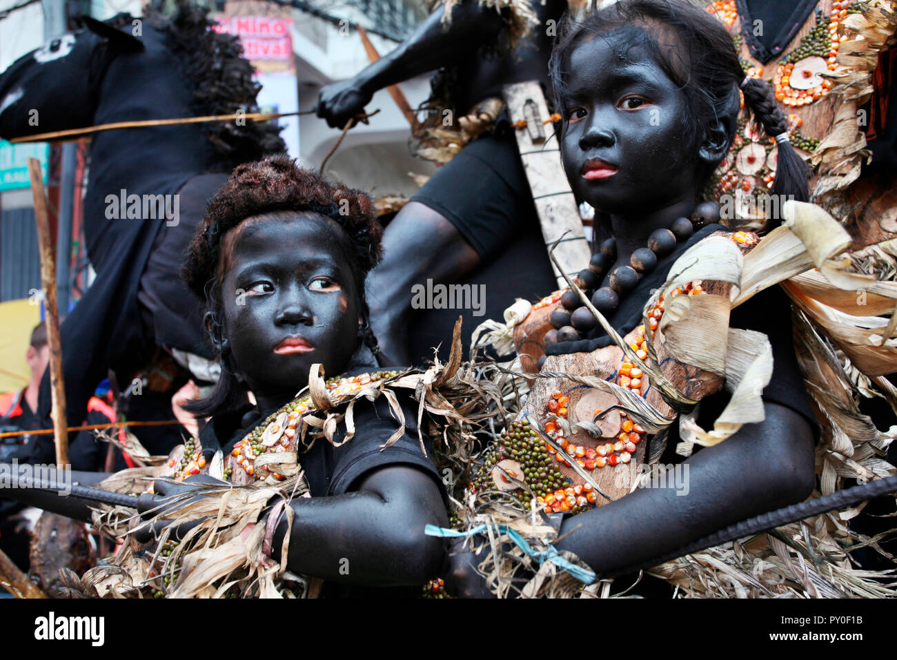 Children with black smeared faces in tribal costumes in front of horseback riding man at Ati Atihan festival, Kalibo, Aklan, Panay Island, Philippines Stock Photo