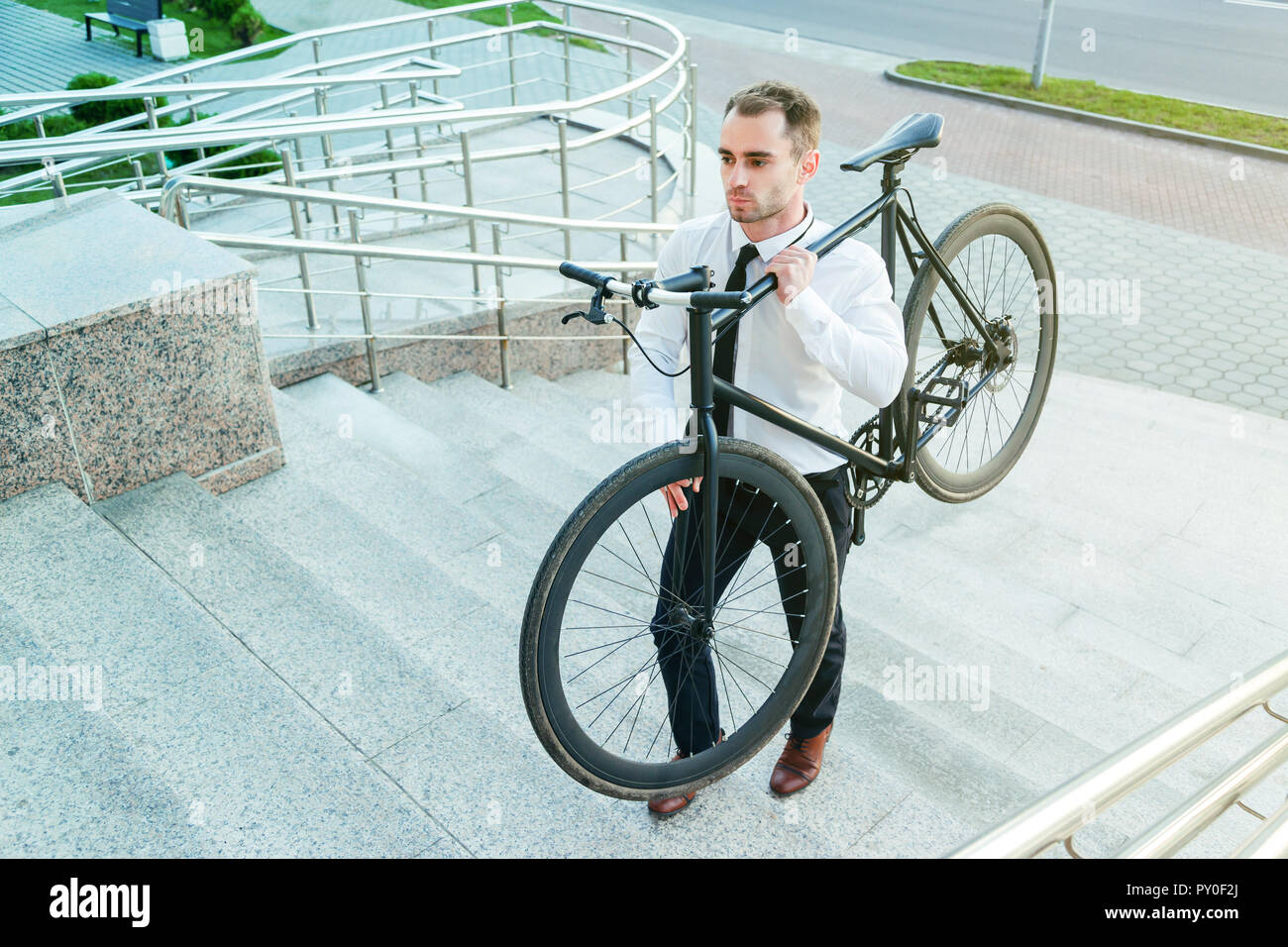 businessman carrying his bike go upstairs Stock Photo