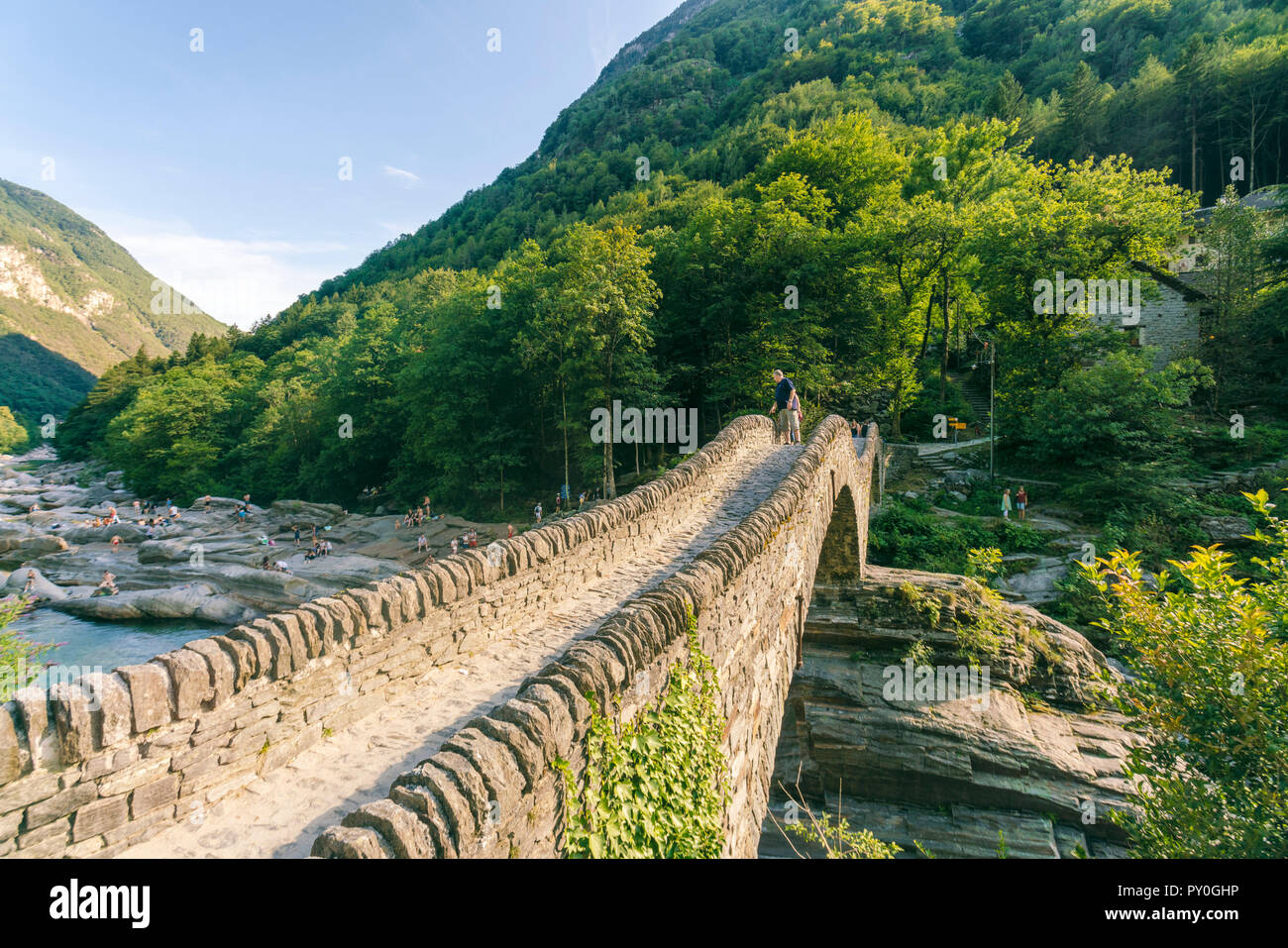 Mountainscape with stoned bridge across river in Alps in summer, Verzasca, Ticino, Switzerland Stock Photo