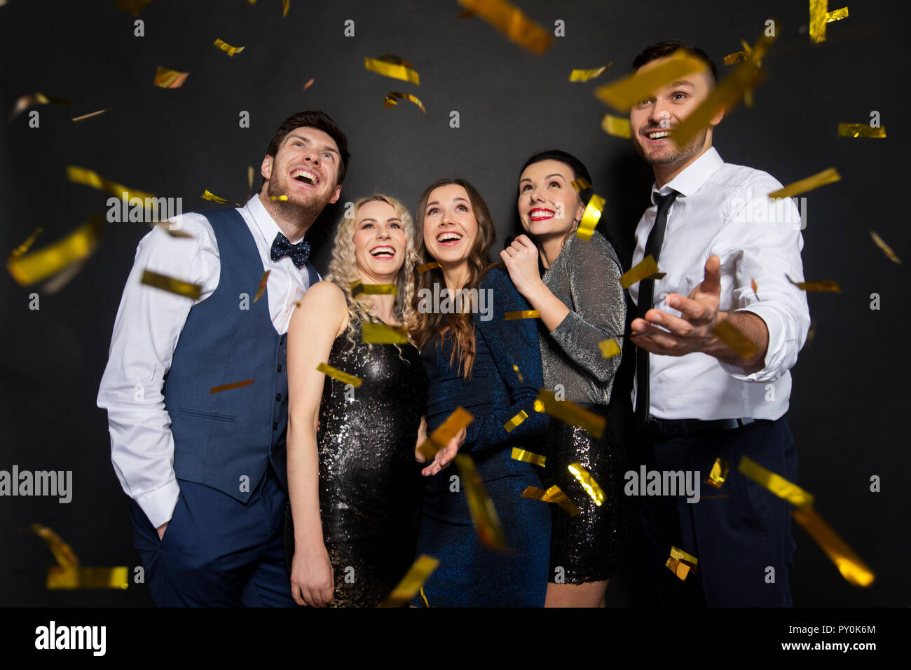 happy friends at party under confetti over black Stock Photo Alamy