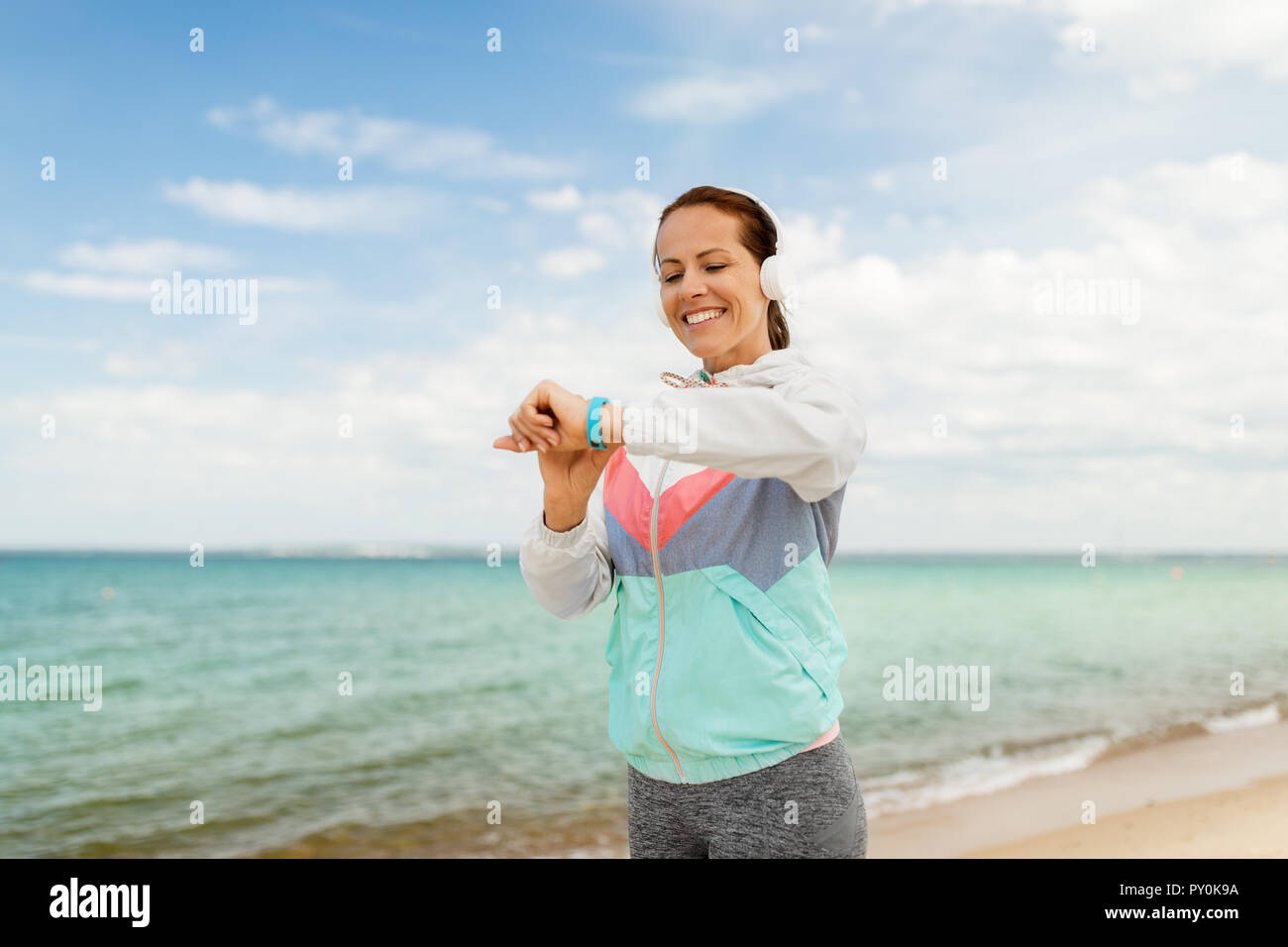 woman with headphones and fitness tracker on beach Stock Photo