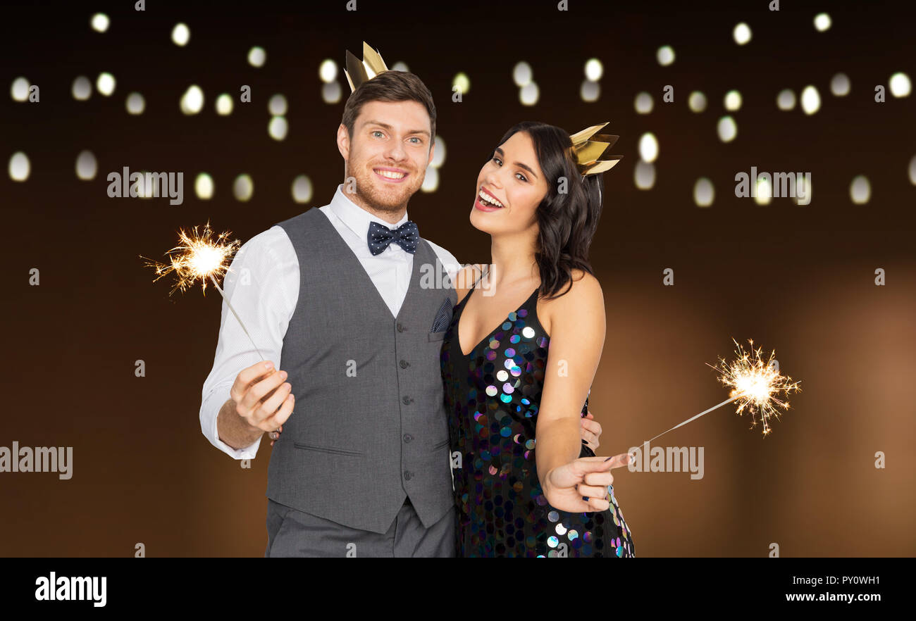 happy couple with crowns and sparklers at party Stock Photo