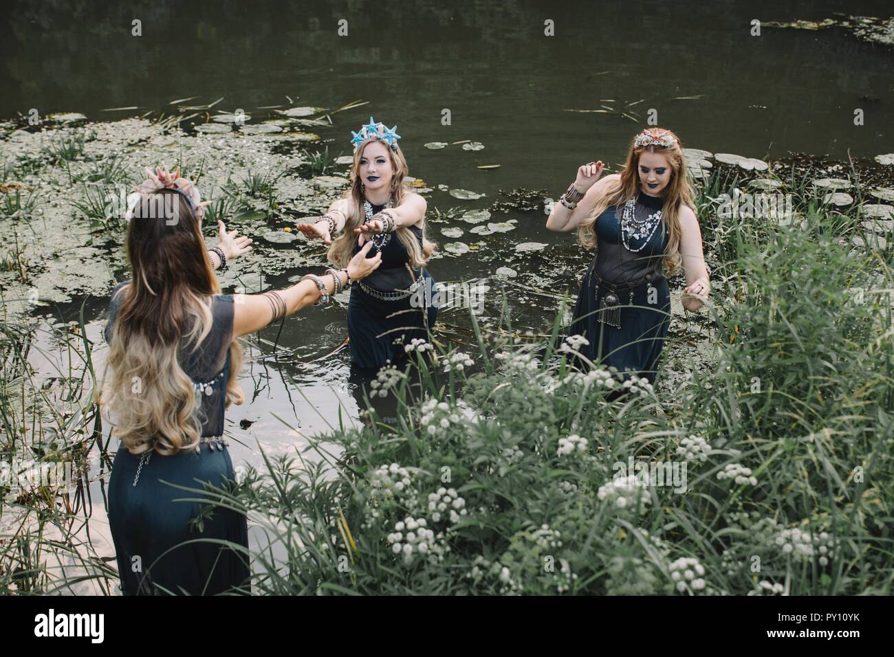 Three boho women dancing in a lake, Russia Stock Photo