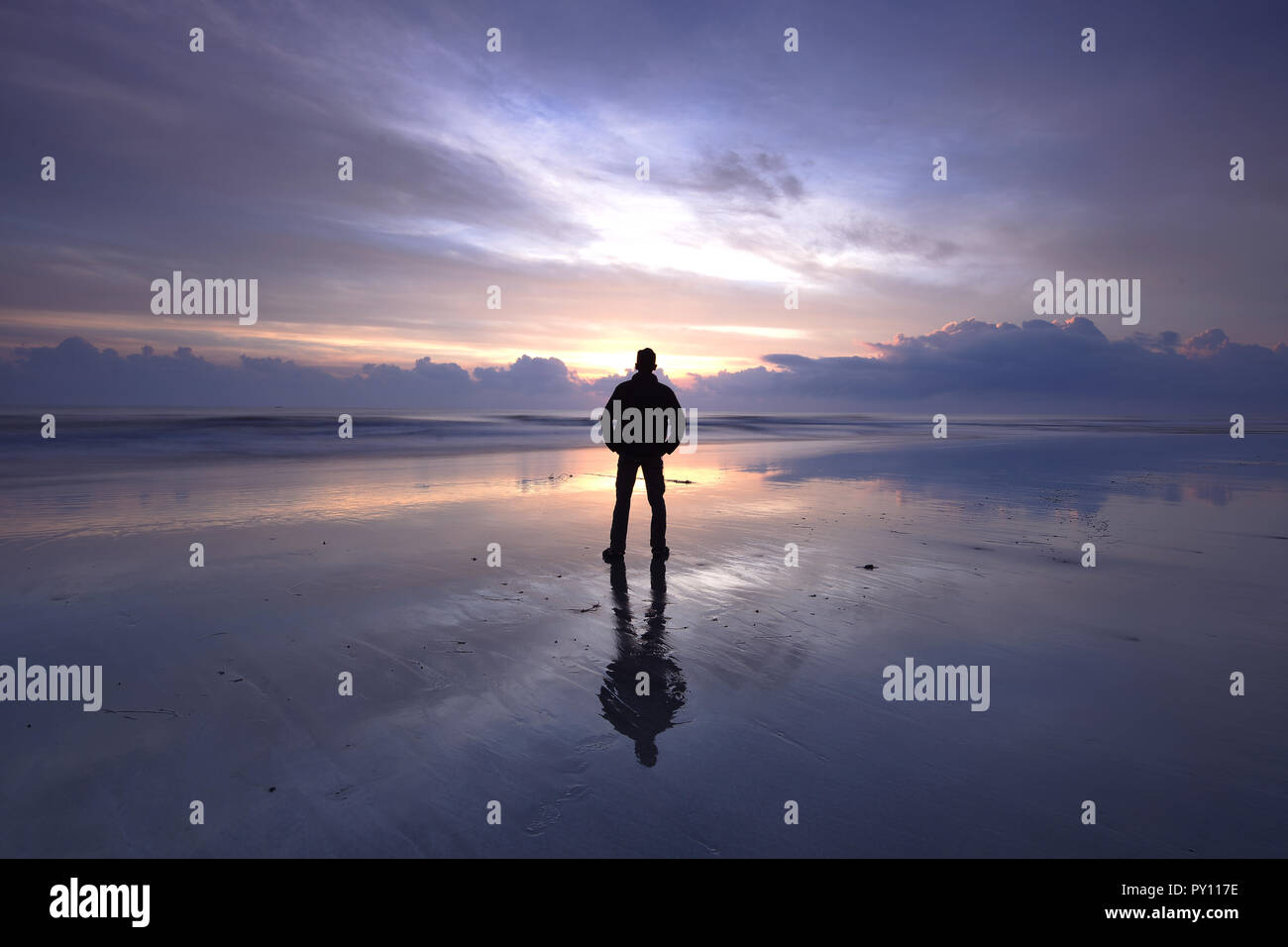 Silhouette of man standing on the beach at sunset, Malaysia Stock Photo ...