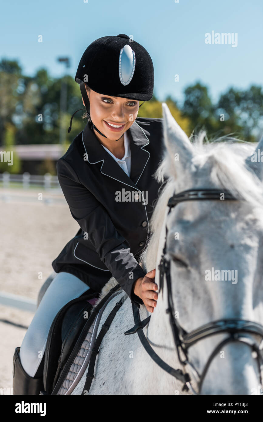 smiling attractive female equestrian in professional apparel riding