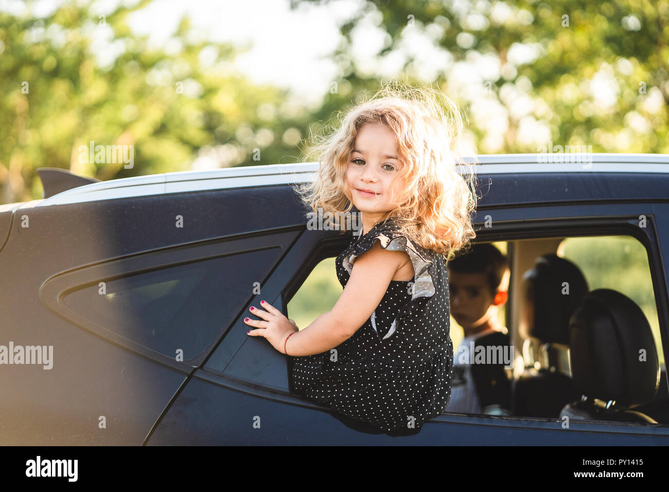 A little girl is sitting on the door of the car Stock Photo - Alamy