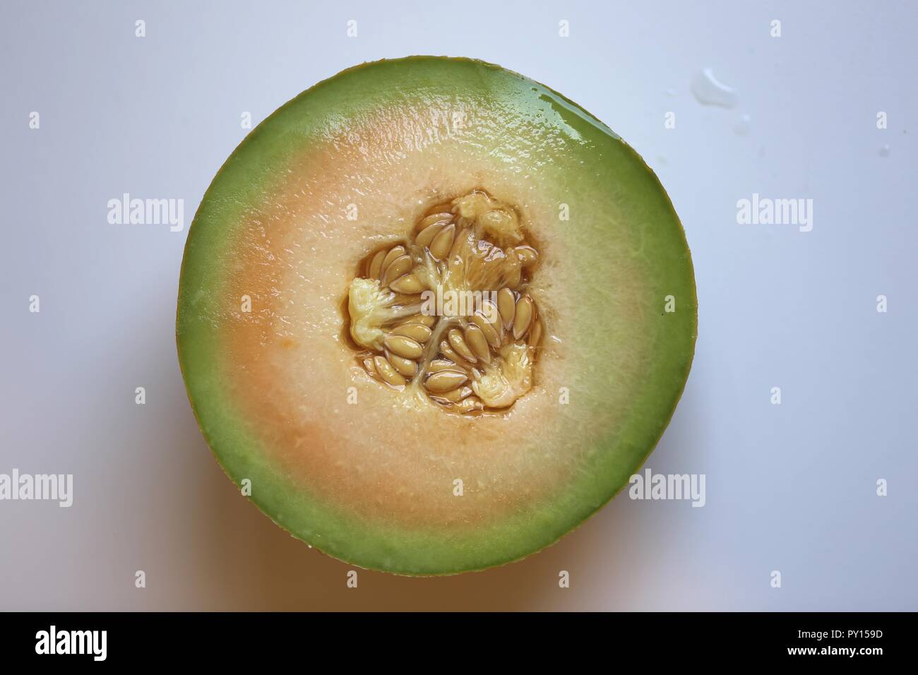 Melon Half, Top View. Fresh orange and green half melon with the seeds and the peel, close up, isolated on bright background. Stock Photo