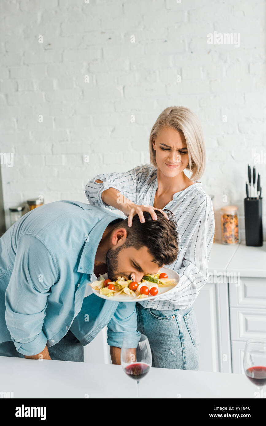 angry girlfriend smashing boyfriend face into salad on plate in kitchen  Stock Photo - Alamy