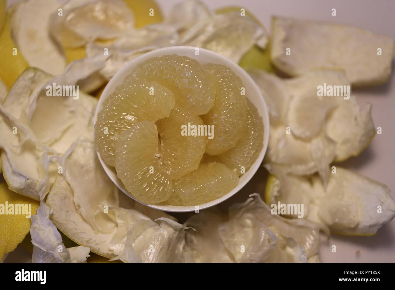 Sweetie. Peeled sweetie slices in a white dish. White bowl full of sliced Sweetie. Hybridization of grapefruit and pomelo. Fresh peeled sweetie. Stock Photo