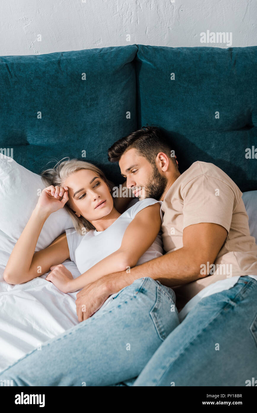 young handsome boyfriend cuddling girlfriend on bed in bedroom Stock