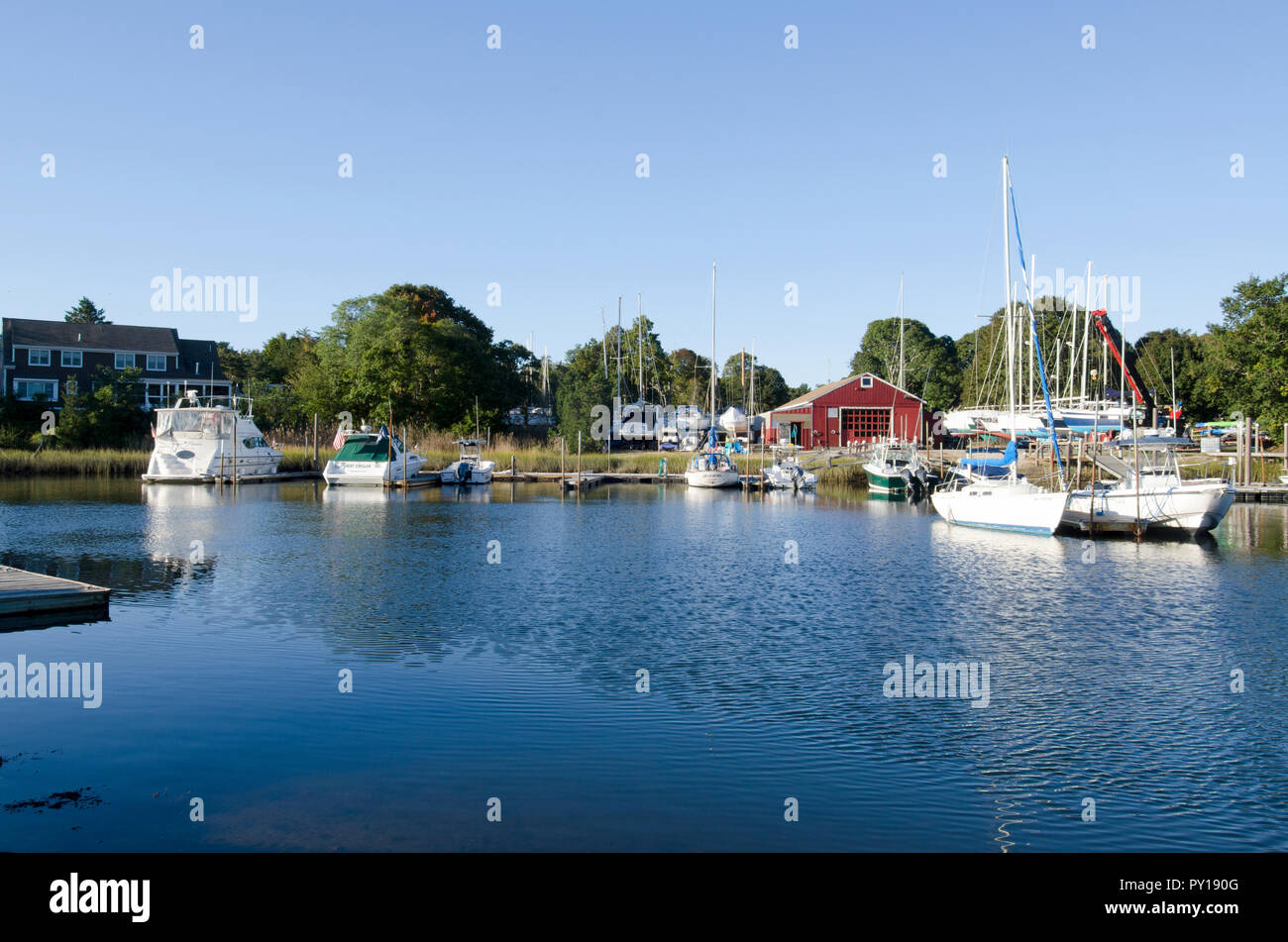 Scenic Pocasset River, Bourne, Cape Cod, Massachusetts, USA with boats docked and boatyard marina beyond on a bright sunny blue sky morning Stock Photo