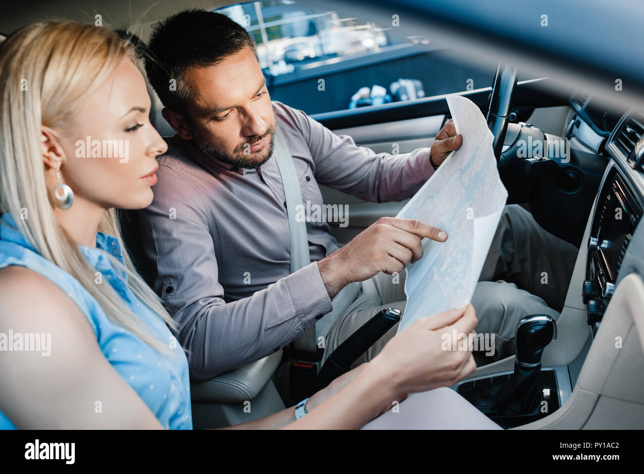 side view of couple looking for destination on map while sitting in car Stock Photo