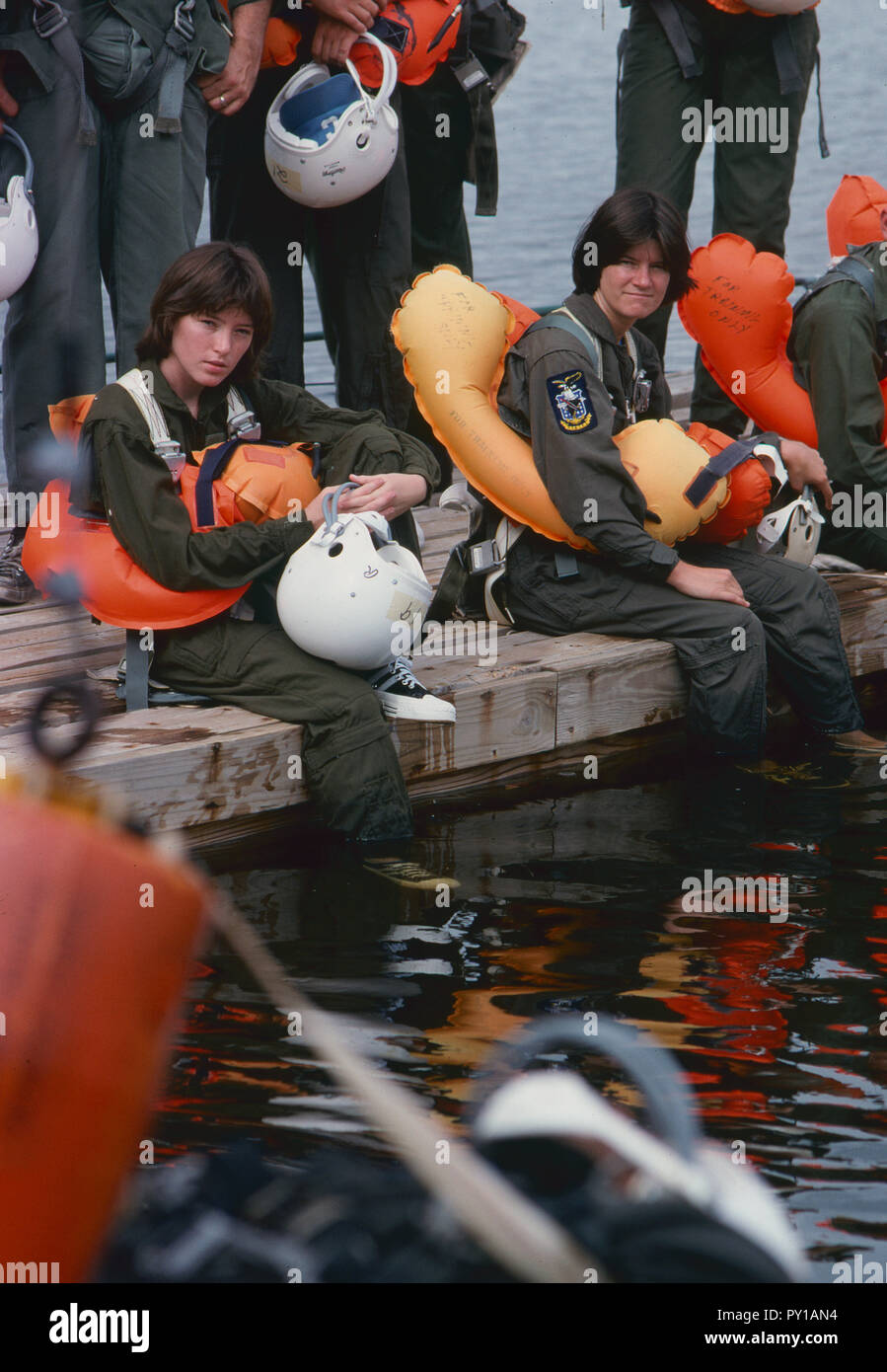 The first female NASA astronauts qualify in Water Survival School at Turkey Point, Florida. Here NASA astronaut candidates (left) Anna L. Fisher and (right) Sally Ride sit among their male classmates as they await their turn in a helicopter water pickup exercise. Stock Photo