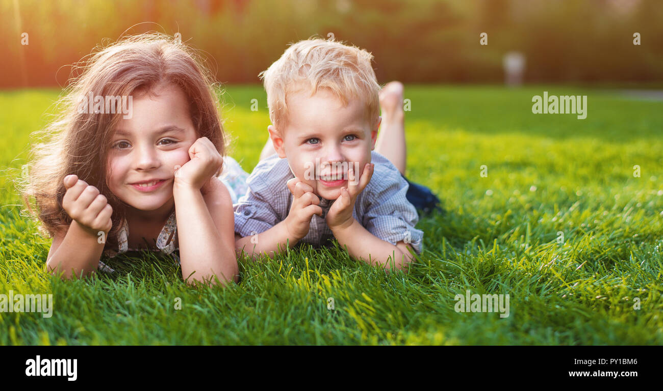 Cheerful little  siblings relaxing on a fresh lawn Stock Photo