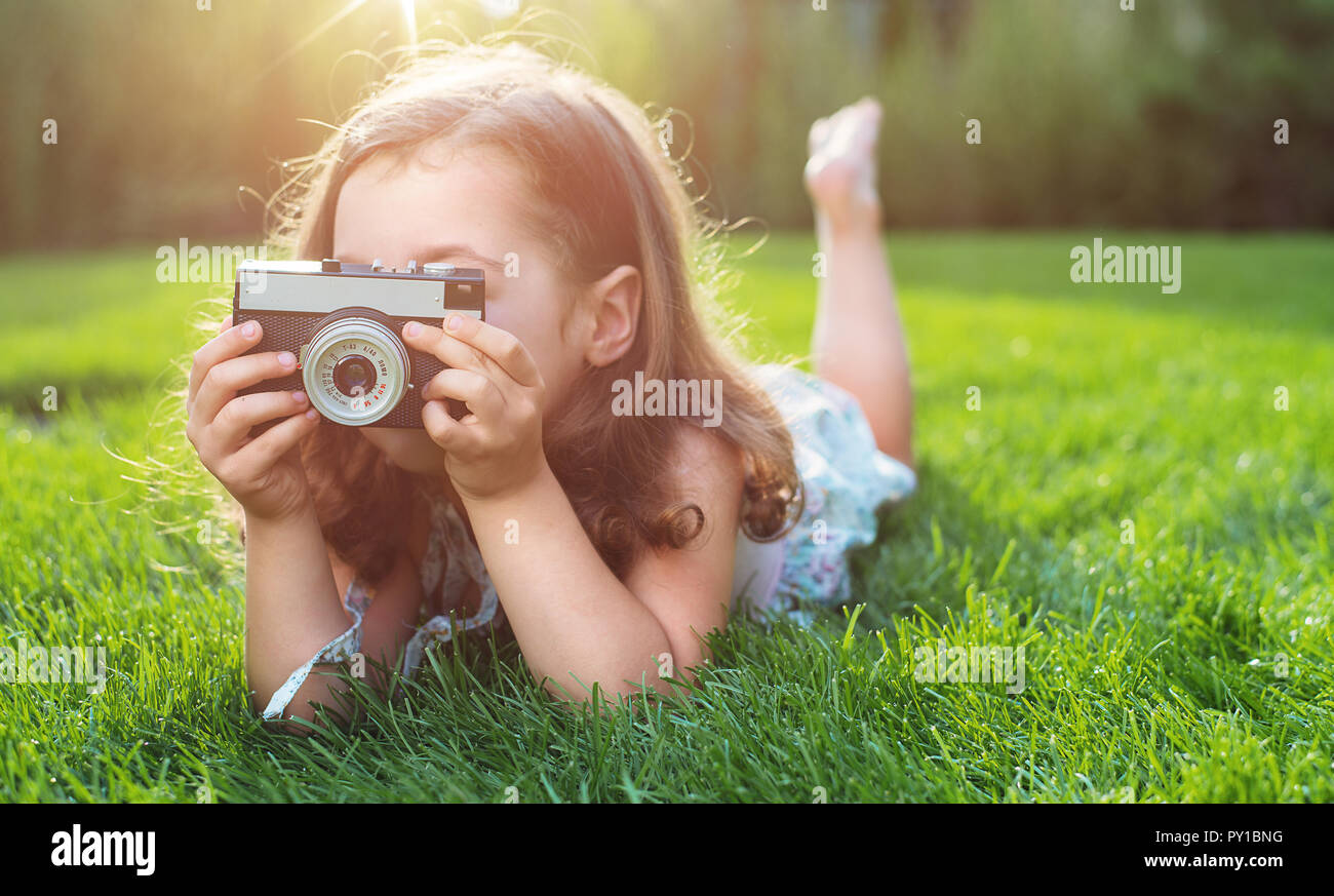 Cute little childl lying on green lawn and taking a picture Stock Photo