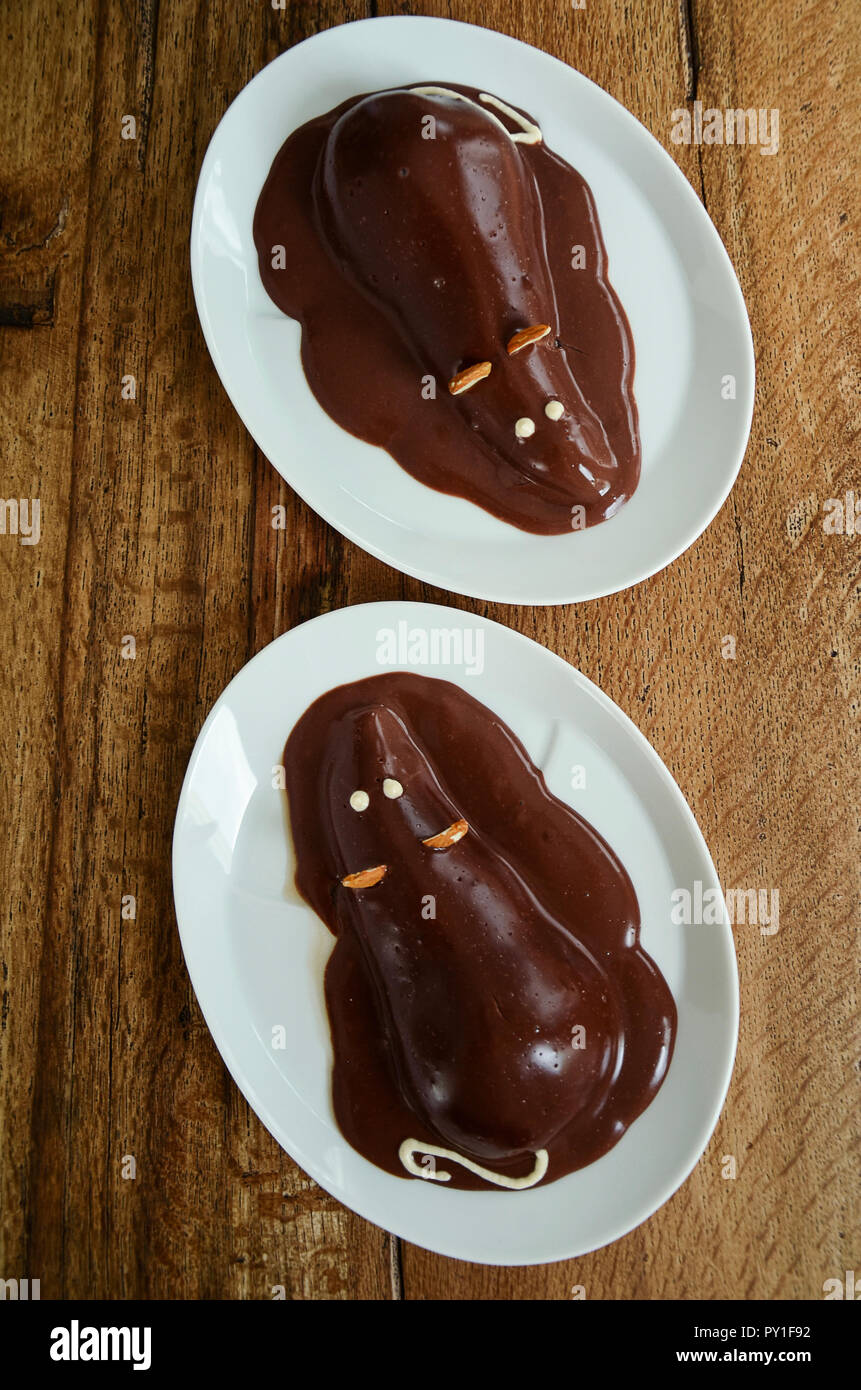 Pear halves coated with chocolate glaze and decorated like a mouse. Creative food, funny dessert for picky eaters. Directly above. Stock Photo