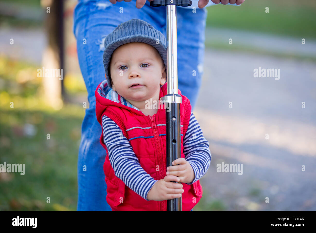 Father riding with his toddler son  scooter in a autumn park. . Active family leisure. Sports, leisure with kids concept. Stock Photo