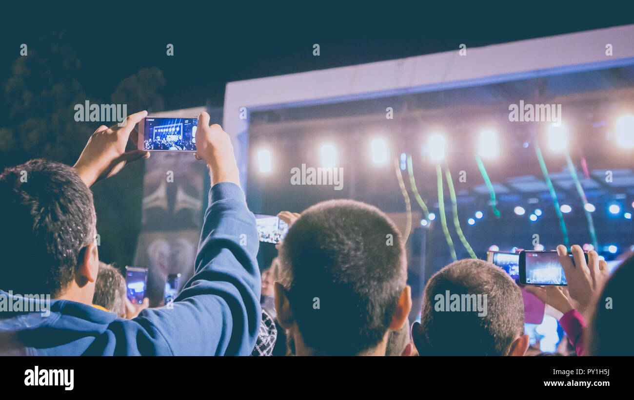 A group of young man recording music event by their mobile phone