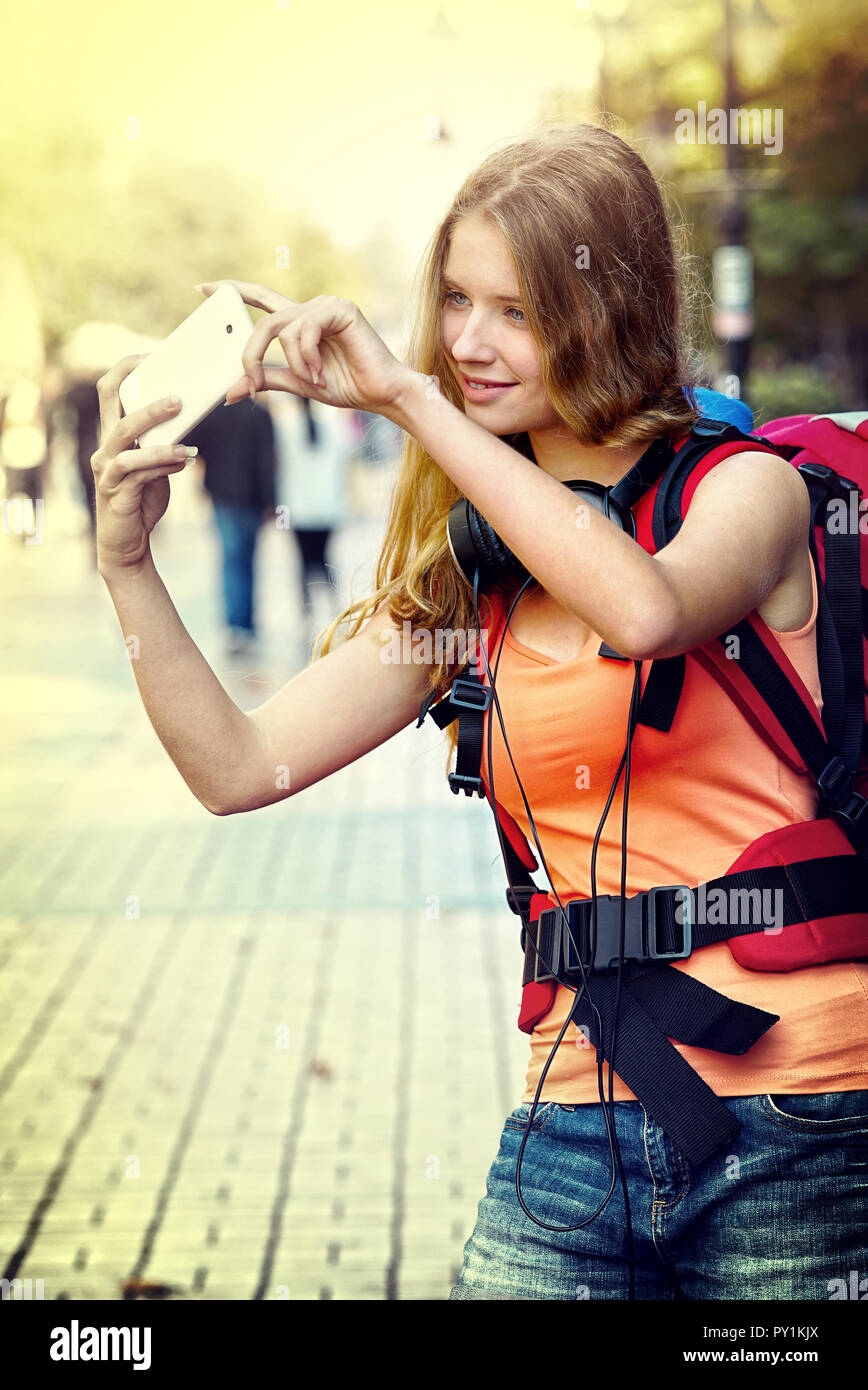 Tourist girl with backpack taking selfies on smartphone Stock Photo
