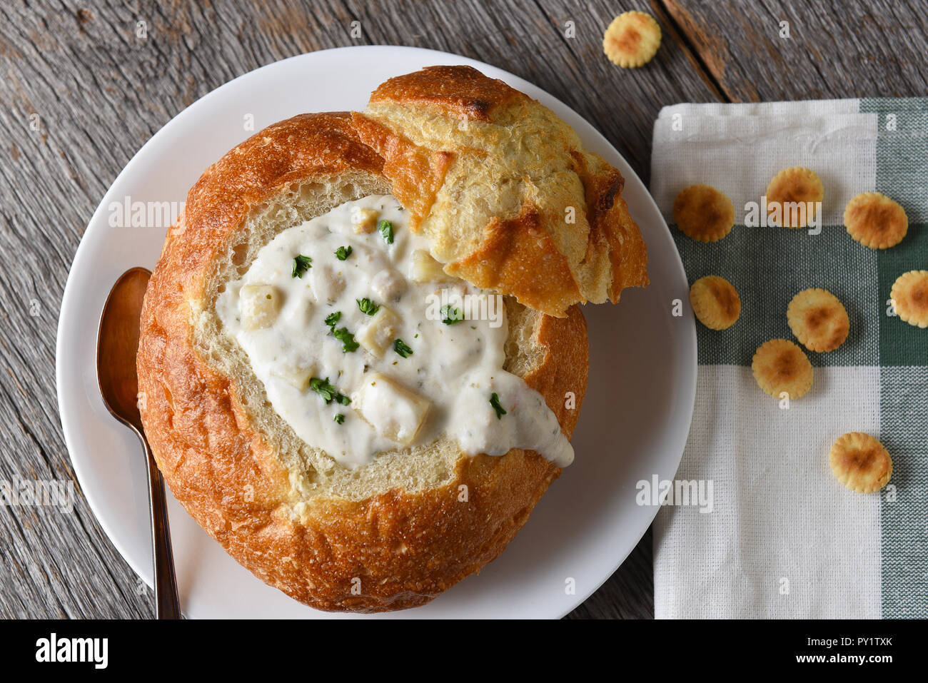 A bread bowl of New England Style Clam Chowder on a rustic wood table