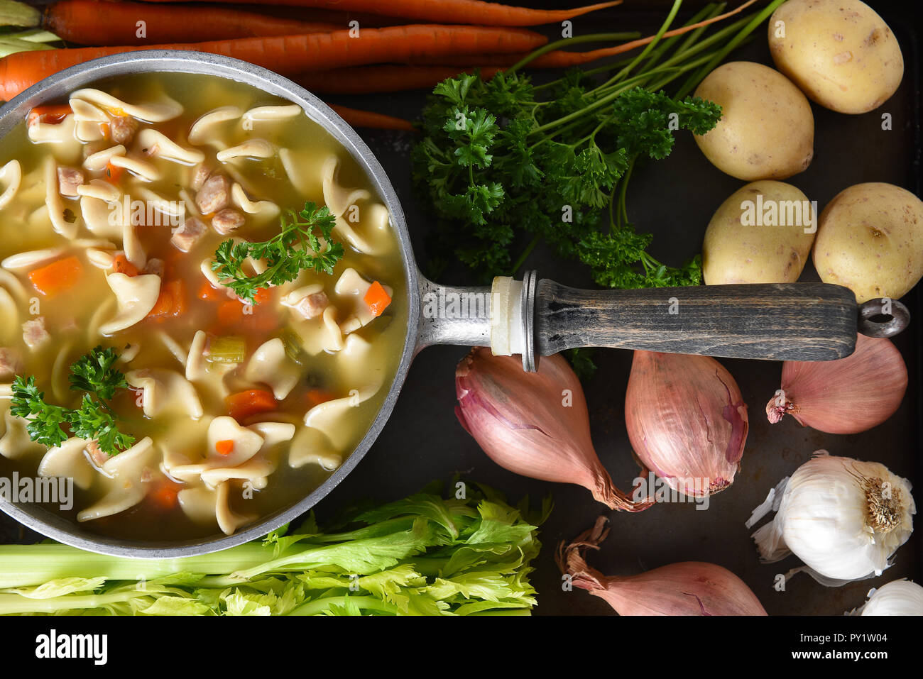 A pot of fresh homemade Chicken Noodle Soup surrounded by some of the ingredients. Stock Photo