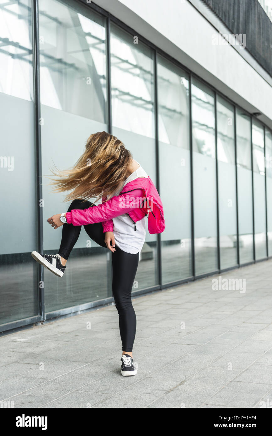 young stylish woman with obscured face by hair dancing at urban street Stock Photo