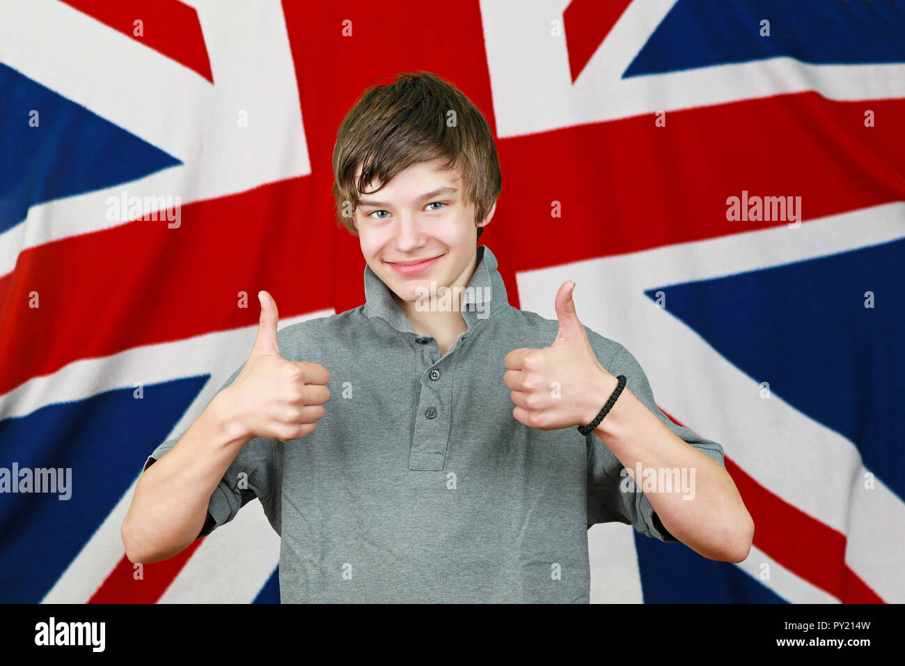 Young British boy with thumbs up in front of Union Jack flag Stock
