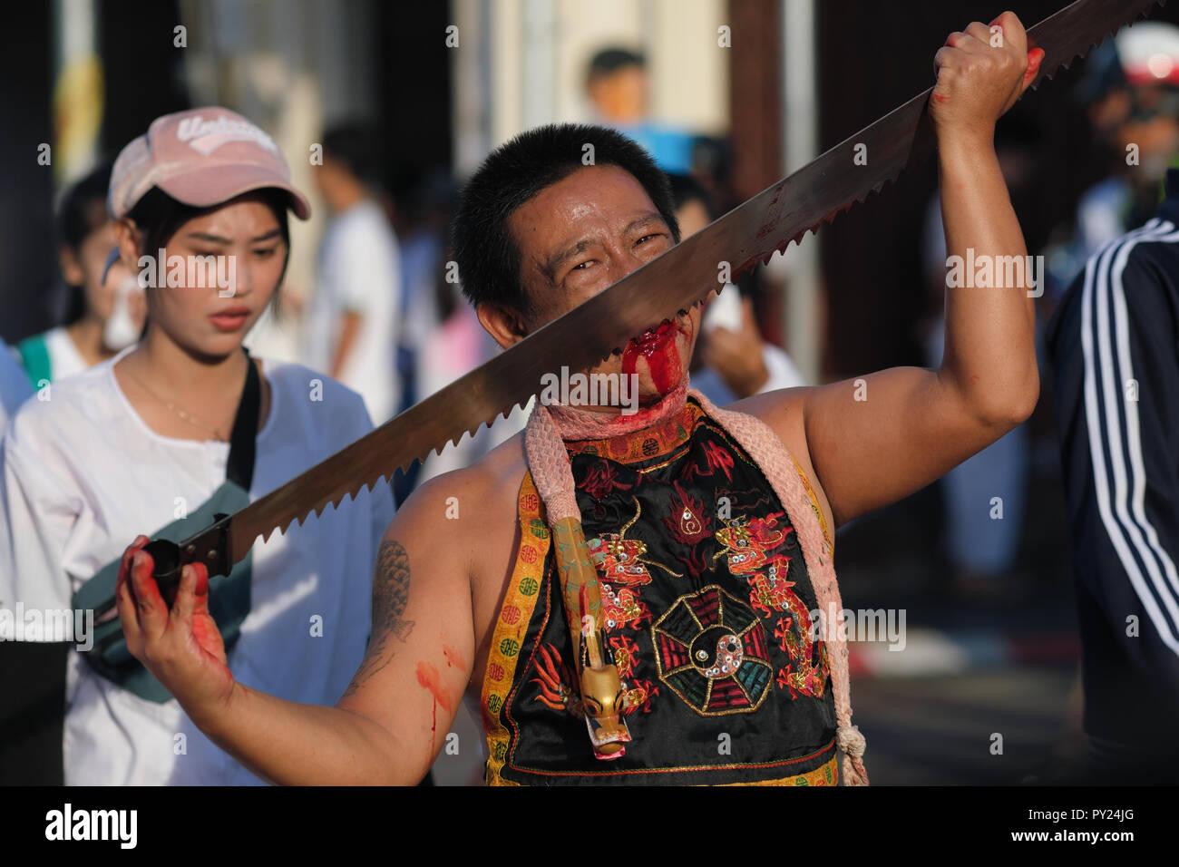 A procession during the Vegetarian Festival in Phuket Town, Thailand, with a Mah Song or spirit medium cutting his tongue with a saw until it bleeds Stock Photo