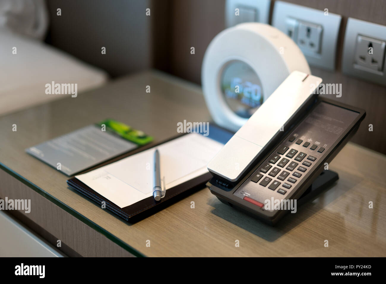 Black telephone and note in front and bed in the background, focus on the telephone,for room service,communication themes in hotel or resort. Stock Photo