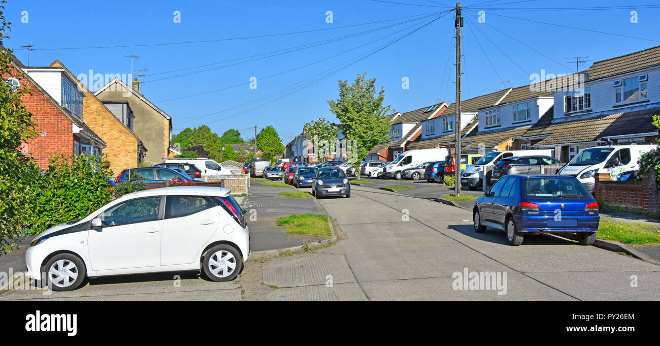 Row of semi detached houses paving over front garden with paved driveway replacing house lawn for some car parking space street scene Essex England UK Stock Photo