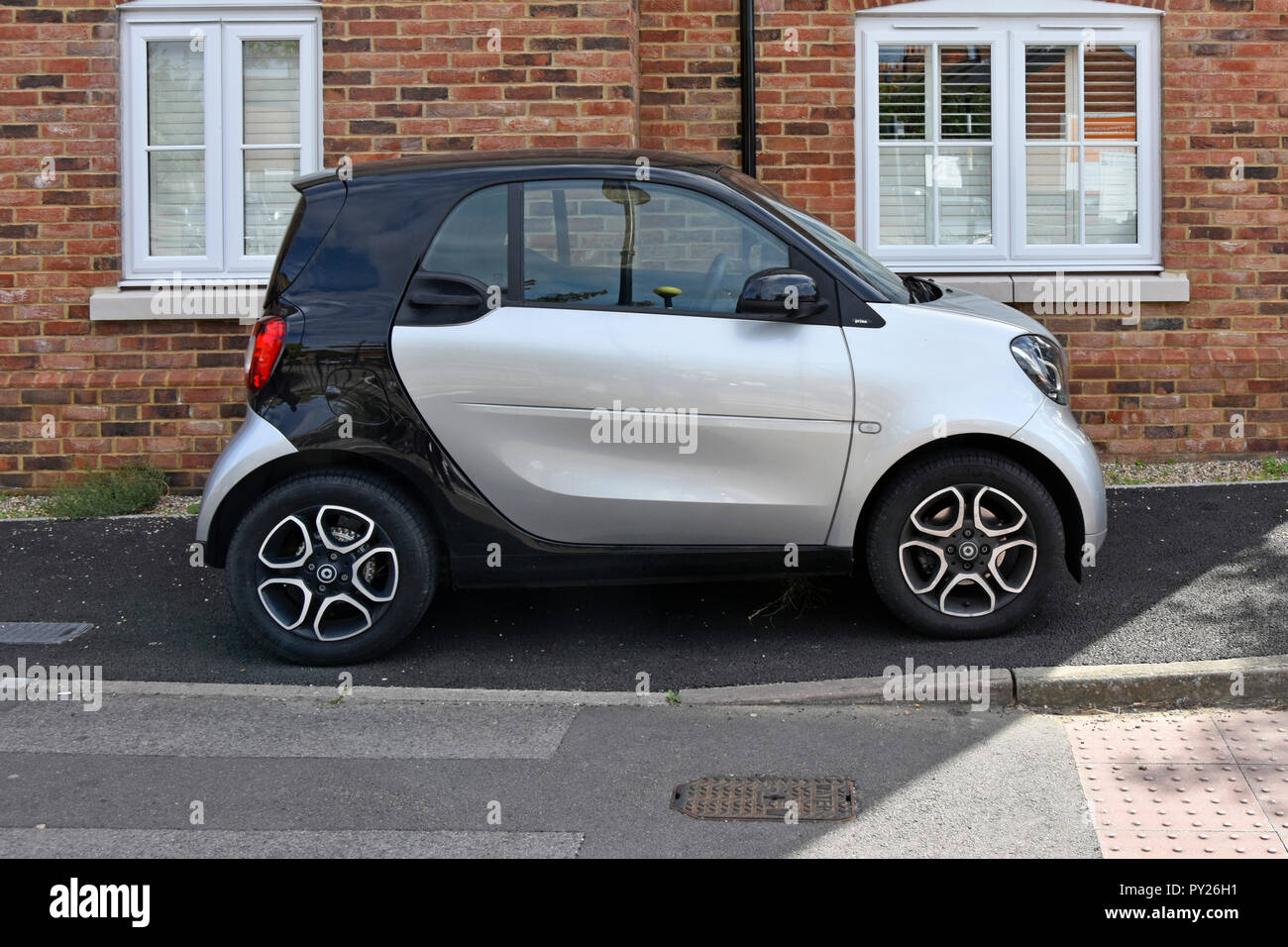 A Daimler Smart small cars compact size fits onto narrow private tarmac pavement car parking spot & space outside apartment window Essex England UK Stock Photo