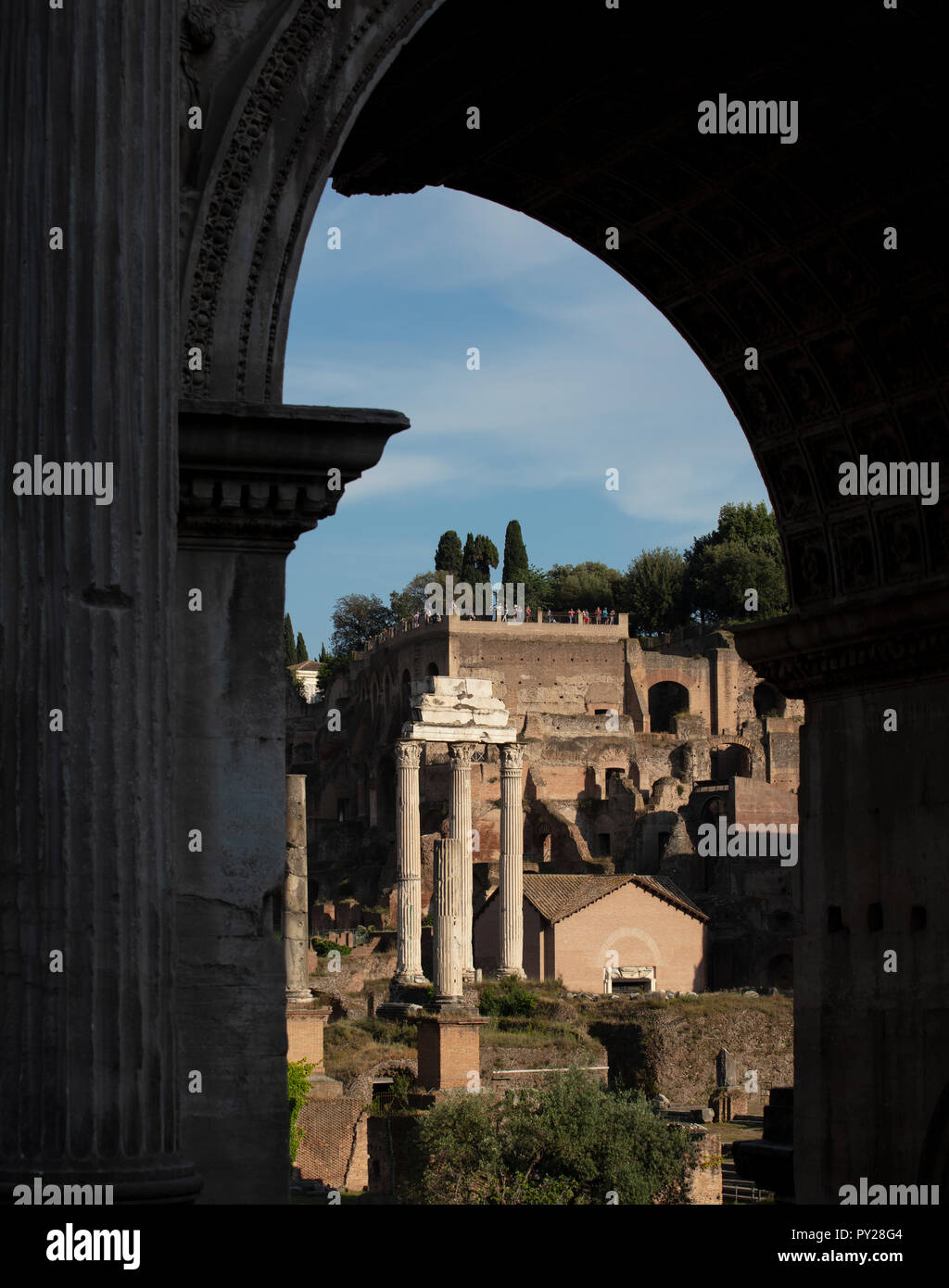 Three surviving columns of the Temple of Castor & Pollux in the ancient Roman forum, seen through the arch of Septimius Severus. Stock Photo