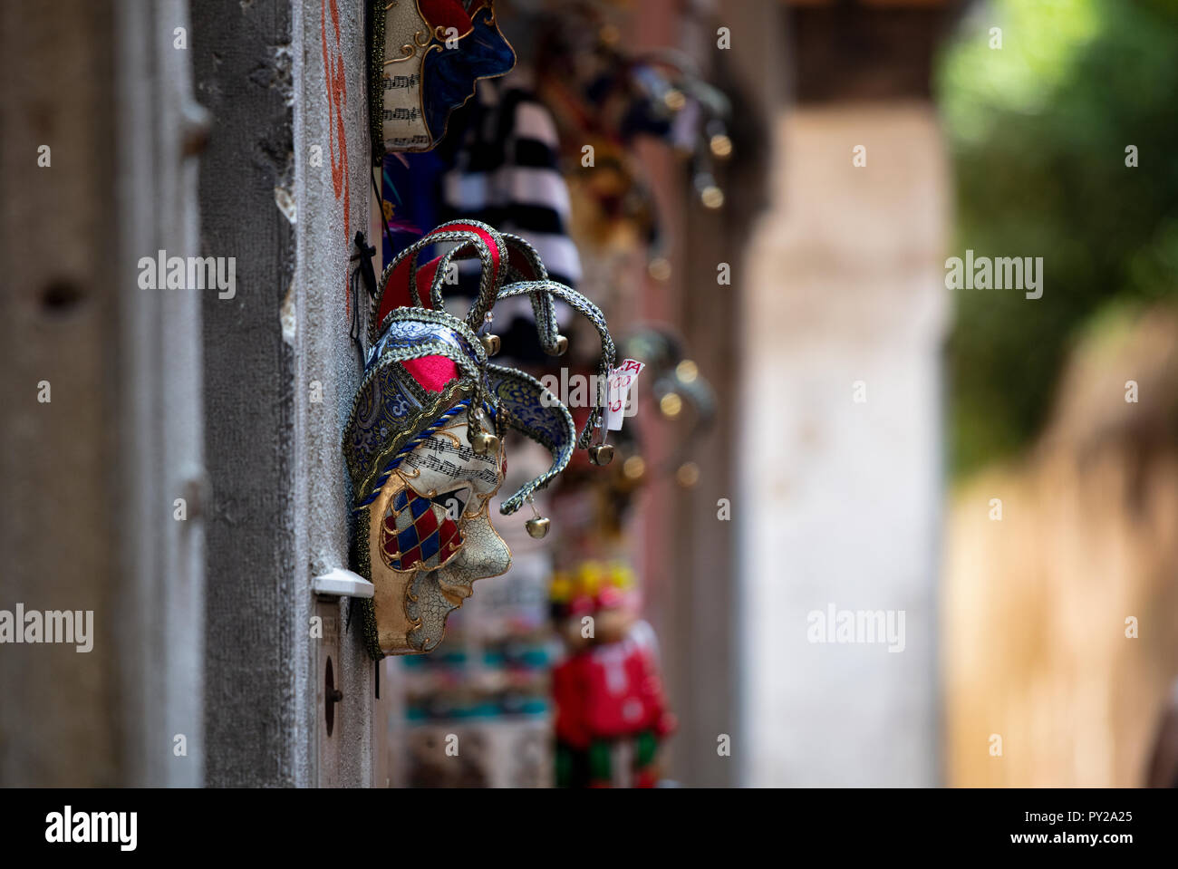 A traditional venetian mask hanging on a shop wall in a quiet street in Venice. Stock Photo