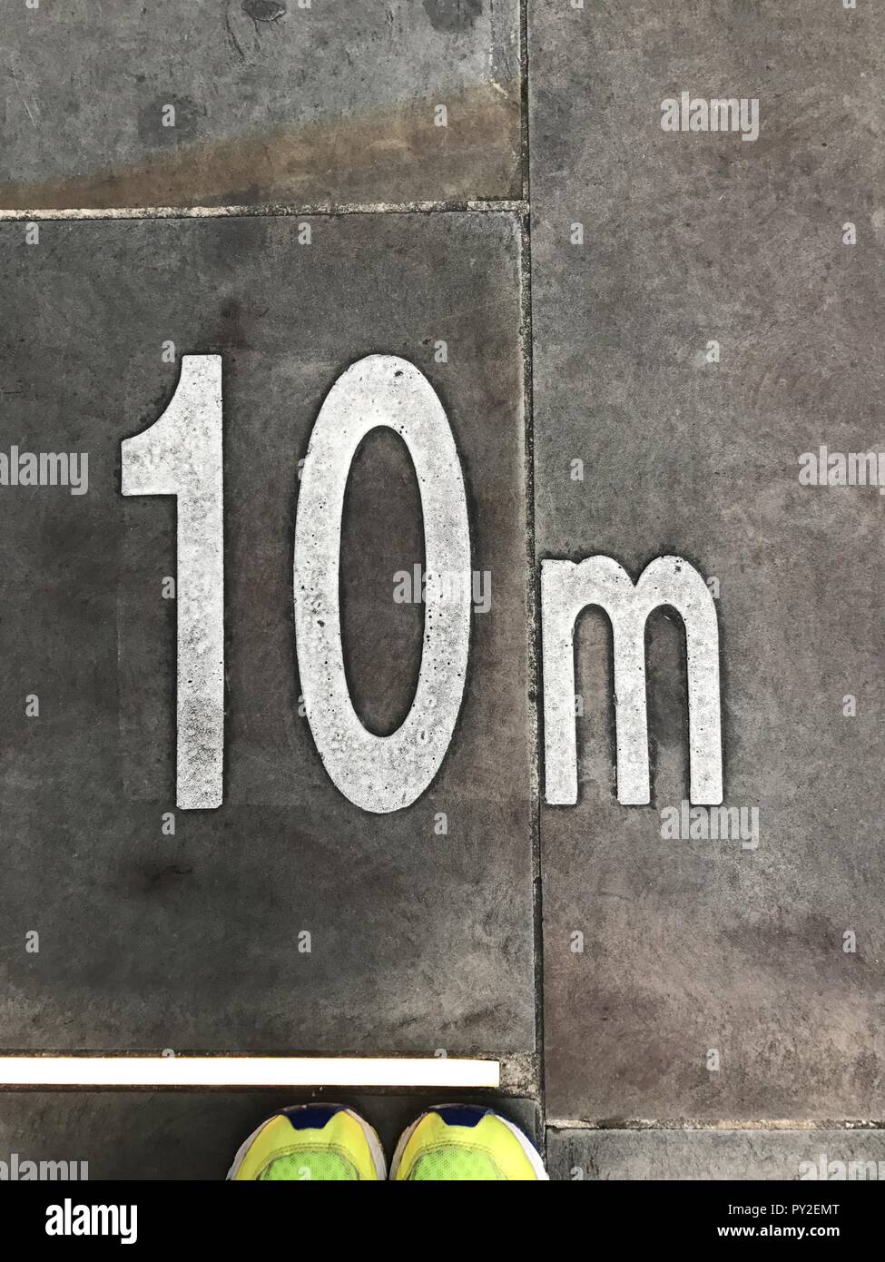 Human feet standing by a 10m marking on the pavement Stock Photo - Alamy