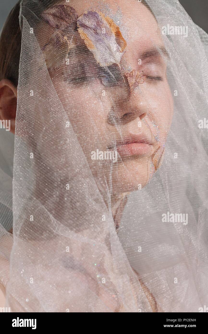 Conceptual beauty portrait of a woman wearing a veil with dried flowers on her face and neck Stock Photo